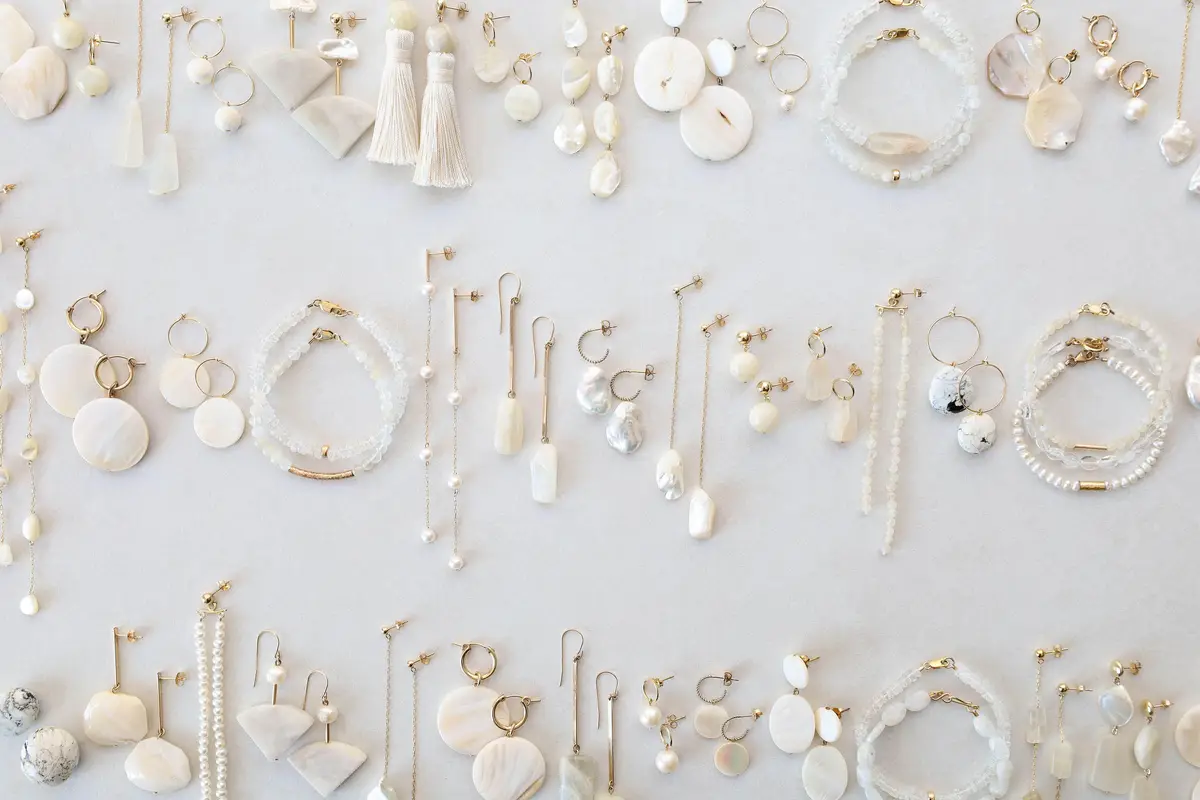 Rows of mother-of-pearl, pearl and moonstone earrings and bracelets on a white surface